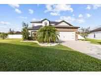 Charming two-story home featuring a well-manicured lawn, stone accents, and a two-car garage at 11841 Thicket Wood Dr, Riverview, FL 33579