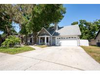 Charming single-story home with a two-car garage and beautifully landscaped front yard with mature trees at 1916 River Crossing Dr, Valrico, FL 33596