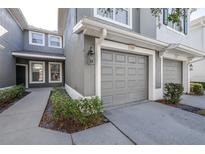 Attached one car gray garage with concrete driveway, and small landscaped area with low bushes at 2150 River Turia Cir, Riverview, FL 33578