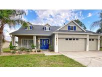 Charming home with a well-manicured lawn, beautiful landscaping, and a striking blue front door at 24314 Landing Dr, Lutz, FL 33559