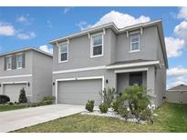 Two story home with gray stucco exterior, light landscaping, and an attached two car garage at 5602 Wandering Willow Dr, Wesley Chapel, FL 33545