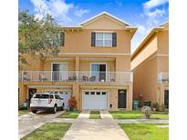Inviting two-story townhome featuring a white balcony, attached garage, and manicured front lawn at 6823 S Kissimmee St, Tampa, FL 33616