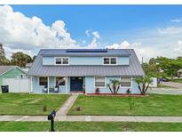 Charming blue two-story home featuring a metal roof, solar panels, and well-manicured lawn at 8439 Boxwood Dr, Tampa, FL 33615