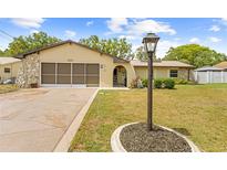 Charming single-story home featuring a well-manicured lawn, decorative stone accents, and a spacious driveway at 9069 Gaynor St, Spring Hill, FL 34608