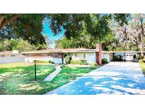Charming single-story home with lush green lawn, mature trees, brick accents, and an attached carport at 13116 N Oregon Ave, Tampa, FL 33612