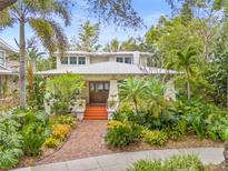 Charming two-story home with lush tropical landscaping, brick walkway, and eye-catching wood door at 1805 W Richardson Pl, Tampa, FL 33606