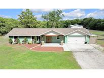 Charming ranch-style home featuring a two-car garage and lush green lawn at 3535 Moores Lake Rd, Dover, FL 33527