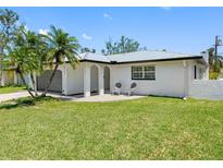 Charming single story home with a manicured lawn, grey metal roof, and front patio at 5731 Denver Ne St, St Petersburg, FL 33703