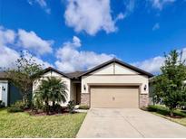 Charming single-story home features a well-manicured lawn and a neutral colored facade with stone accents at 6293 Bradford Woods Dr, Zephyrhills, FL 33542