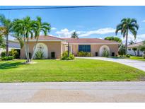 Charming single-story home with well-manicured lawn, circular driveway, and tasteful landscaping, including palm trees at 890 Coronado Dr, Punta Gorda, FL 33950