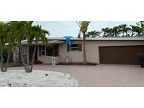 Charming single-story home with brick driveway and lush palm trees in a tropical setting at 997 Boca Ciega Isle Dr, St Pete Beach, FL 33706
