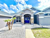 Charming home exterior showcasing a stone-accented entrance and a vibrant blue double-door entry at 11268 Shivering Owl Ave, Weeki Wachee, FL 34614