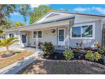 Charming home featuring a cozy front porch with stylish seating and well-maintained landscaping at 1422 Pinebrook Dr, Clearwater, FL 33755