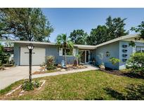 Charming single-story home with a well-manicured lawn and cute tropical landscaping in front at 1942 Ashland Dr, Clearwater, FL 33763