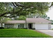 Charming single-story home featuring a stone facade, a two-car garage, and a lush front lawn under a large tree at 2004 Chickwood Ct, Tampa, FL 33618