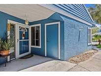 Charming blue home entrance with a storm door, side window and separate storage entrance at 2023 Golfview Dr # 2023, Tarpon Springs, FL 34689