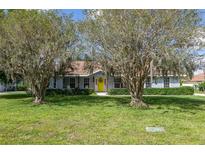 Inviting single-story home featuring a bright yellow door, covered porch, and mature trees in a lush front yard at 206 147Th E St, Bradenton, FL 34212