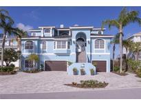 Stunning light blue two-story home featuring a two-car garage, brick driveway and elegant staircase to the front door at 2111 Alexis Ct, Tarpon Springs, FL 34689