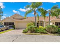 Charming single story home with attached garage, manicured landscaping, and a brick paved driveway at 2471 New Haven Cir, Sun City Center, FL 33573