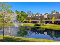Modern townhomes overlook a scenic pond with fountain and rainbow, surrounded by lush landscaping on a clear day at 4118 Gauge Line Loop, Tampa, FL 33624