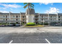Three-story condo building with private balconies, covered parking, and a well-maintained lawn at 8765 Bardmoor Blvd # 107, Seminole, FL 33777