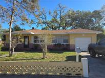 Charming single-story home with a well-maintained lawn, mature trees, and a convenient attached garage at 1125 Engman St, Clearwater, FL 33755