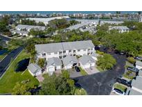 An aerial view of charming townhouses with garages, lush landscaping, and water views in the distance at 11520 Shipwatch Dr # 1385, Largo, FL 33774