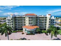 Beautiful multi-story condo building near the beach with a circular driveway, lush landscaping, and ample parking at 11605 Gulf Blvd # 203, Treasure Island, FL 33706