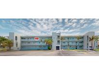 Exterior of a light blue condo building featuring balconies and palm trees in a sunny neighborhood at 12405 3Rd E St # 306, Treasure Island, FL 33706