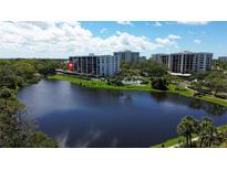 Scenic view of the condominium complex and its community pool, set by a serene lake at 220 Belleview Blvd # 104, Belleair, FL 33756