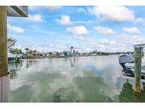 A waterfront view featuring a boat docked alongside waterfront homes under a sunny, partly cloudy sky at 7889 3Rd S Ave, St Petersburg, FL 33707
