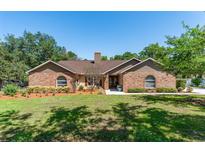 Charming brick home featuring a well-manicured lawn, complemented by mature trees and lush landscaping at 12408 Wexford Hills Rd, Riverview, FL 33569