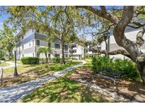Beautiful condo exterior with a walkway, mature trees, and lush landscaping offering a tranquil setting at 2650 Countryside Blvd # B-110, Clearwater, FL 33761