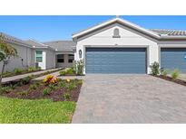 Beautiful single-story home featuring a blue garage door, tile roof, and landscaped front yard at 27153 Capri Shores Cir, Englewood, FL 34223