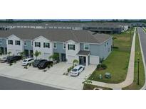 Aerial view of community townhomes featuring attached garages and well-maintained landscaping at 33083 Frosted Clover Way, Wesley Chapel, FL 33545