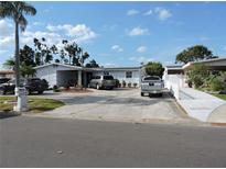 Charming single-story home with a large driveway, complemented by manicured landscaping and a palm tree at 4529 W Knox St, Tampa, FL 33614