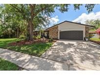 Charming home featuring a stone accent facade, a two-car garage, and a well-manicured lawn with mature trees at 50 Pine Lake Dr, Oldsmar, FL 34677