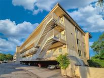 Low-angle view of a four-story building with open parking and staircase at 55 Harbor View Ln # 108, Belleair Bluffs, FL 33770