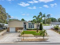 Inviting front exterior with manicured lawn, palm trees, and unique architectural details under a partly cloudy sky at 6630 Gulfport S Blvd, South Pasadena, FL 33707
