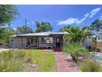 Charming home with a brick walkway, lush landscaping, palm trees, and metal roof creates wonderful curb appeal at 6920 Bougainvilla S Ave, St Petersburg, FL 33707