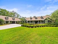 Beautiful one-story home with a manicured front lawn, long driveway and porte cochere at 876 Ranch Rd, Tarpon Springs, FL 34688