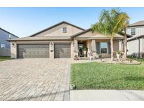 Charming single-story home featuring a three-car garage, stone driveway, and a neatly manicured front lawn at 14413 Seattle Slew Ln, Ruskin, FL 33573
