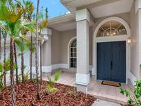 Inviting front entrance featuring an arched double door, a decorative window and lovely landscaping at 3728 Cypress Meadows Rd, Tampa, FL 33624