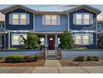 Charming blue townhome featuring a red door, white trim, and a landscaped front yard with a decorative fence at 414 Finn Way # 4, Dunedin, FL 34698