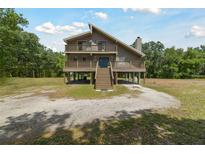 Inviting two-story home with wraparound porch, set on stilts, blending architectural design and outdoor living at 7606 Four Pines Rd, Plant City, FL 33565