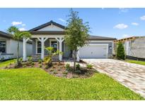 Charming single-Gathering home featuring a well-manicured lawn and a brick-paved driveway leading to a two-car garage at 10317 Cross River Trl, Parrish, FL 34219