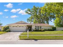 Charming single-story home featuring a well-manicured lawn, mature trees, and an attached two-car garage at 2961 Stockwood Dr, Clearwater, FL 33761