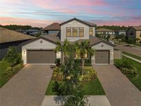 Beautiful two-story home featuring a three car garage, a brick paved driveway, and lush landscaping at 4365 Frontera Ln, Wesley Chapel, FL 33543