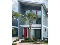 Modern two-story home featuring a red front door, large windows, and a well-manicured front yard with a palm tree at 5768 75Th N Ter, Pinellas Park, FL 33781