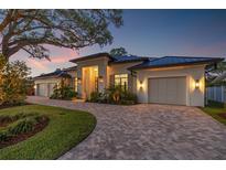 Stunning home exterior featuring a brick driveway, manicured lawn, and warm lighting accentuating the façade at 634 Poinsettia Rd, Belleair, FL 33756